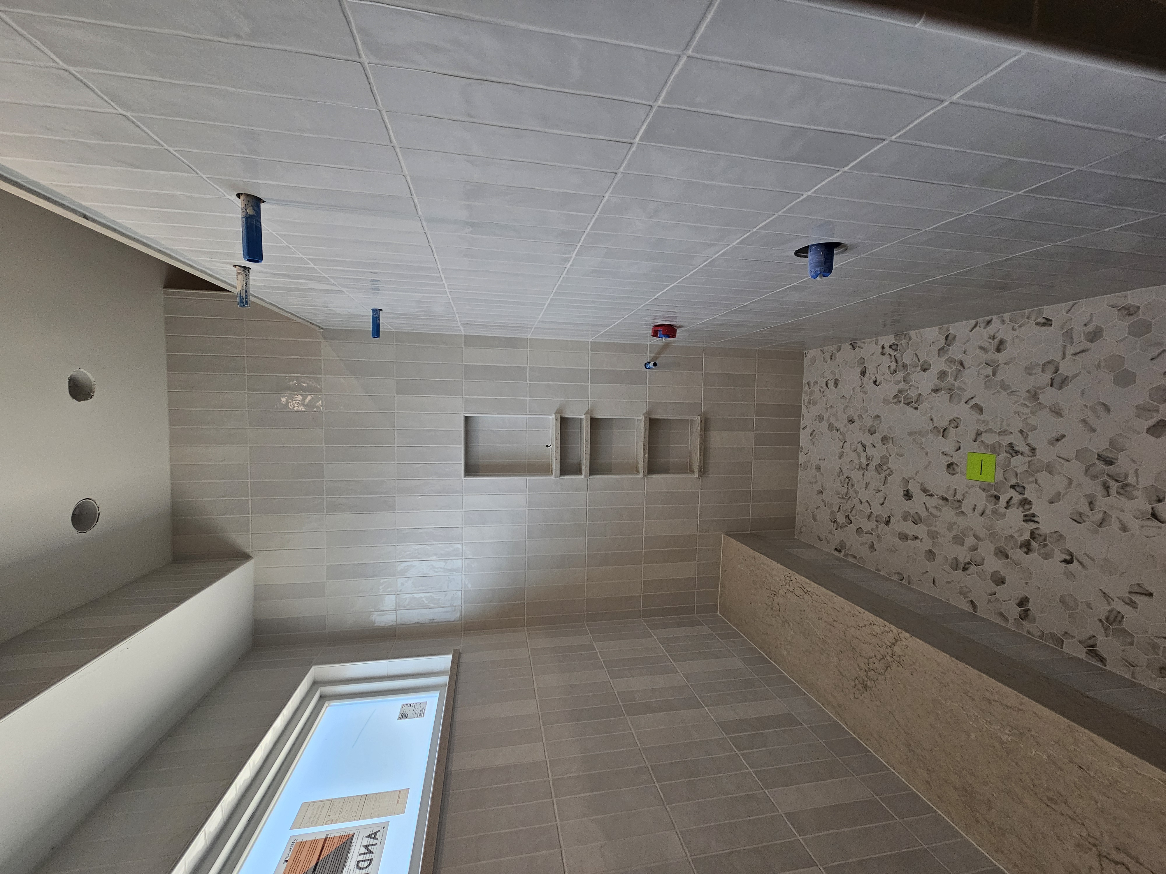 Large walk-in shower with vertical stacked tile, stone bench, and niche