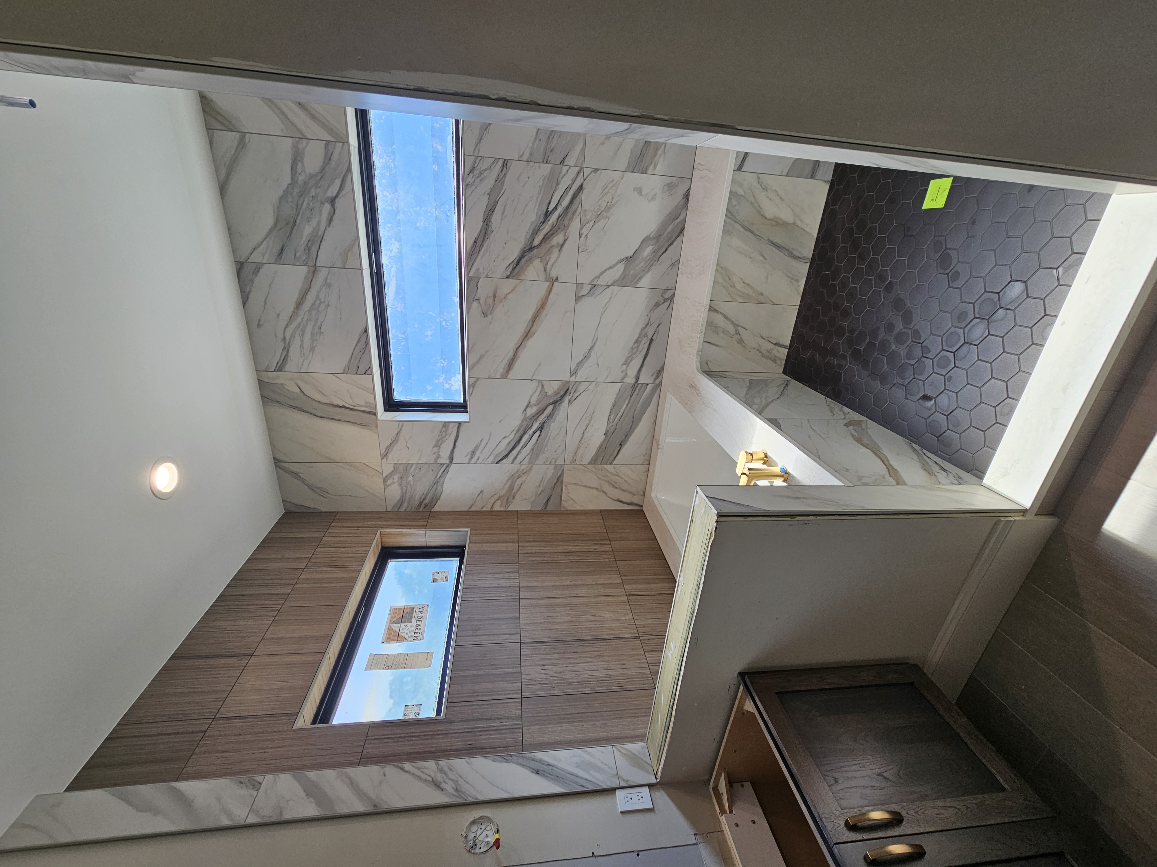 Huge wet room with tub, wood-look accent wall, and continuous stone slab bench